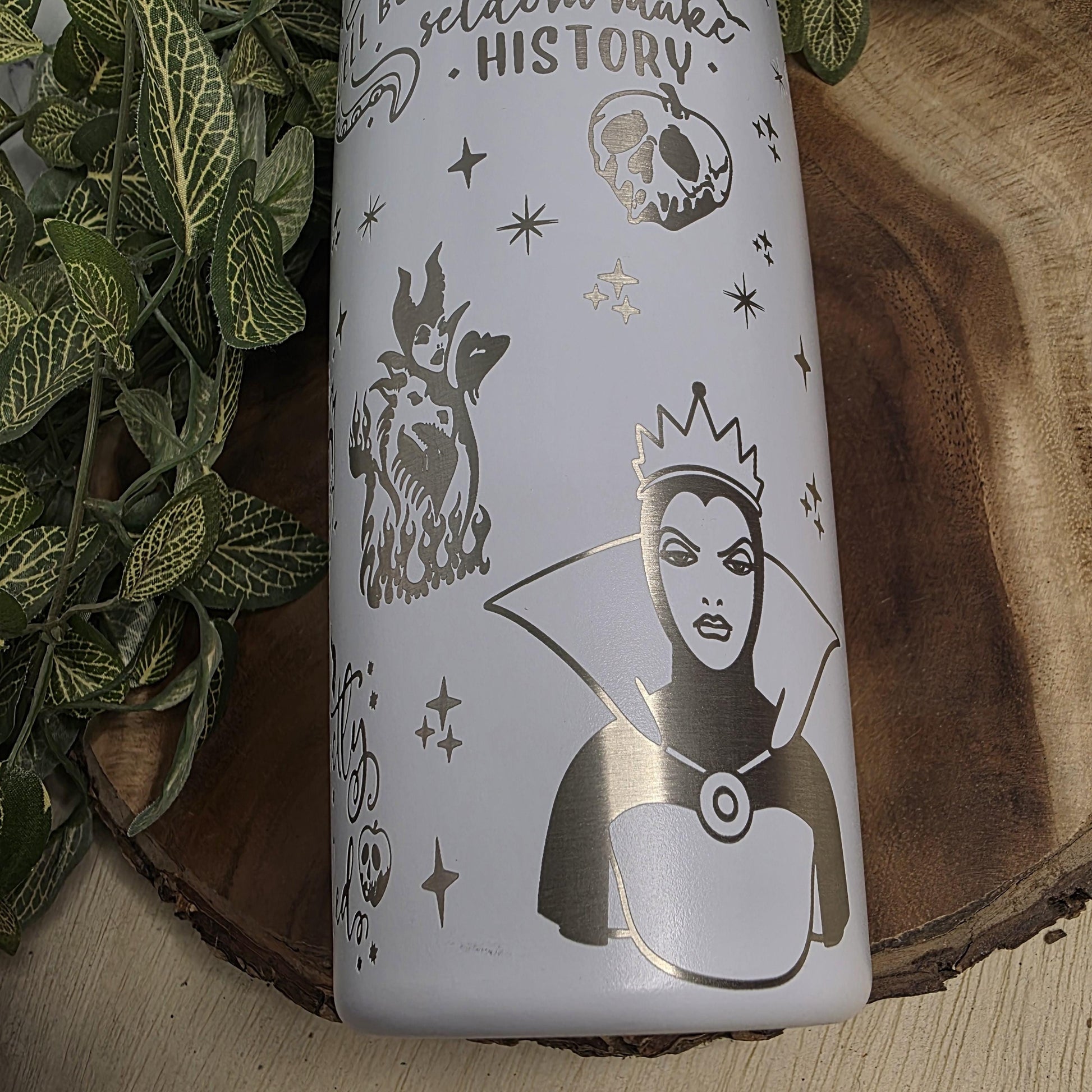 a white ceramic object with a silver design depicting a woman with a crown, surrounded by stars and leaves.
