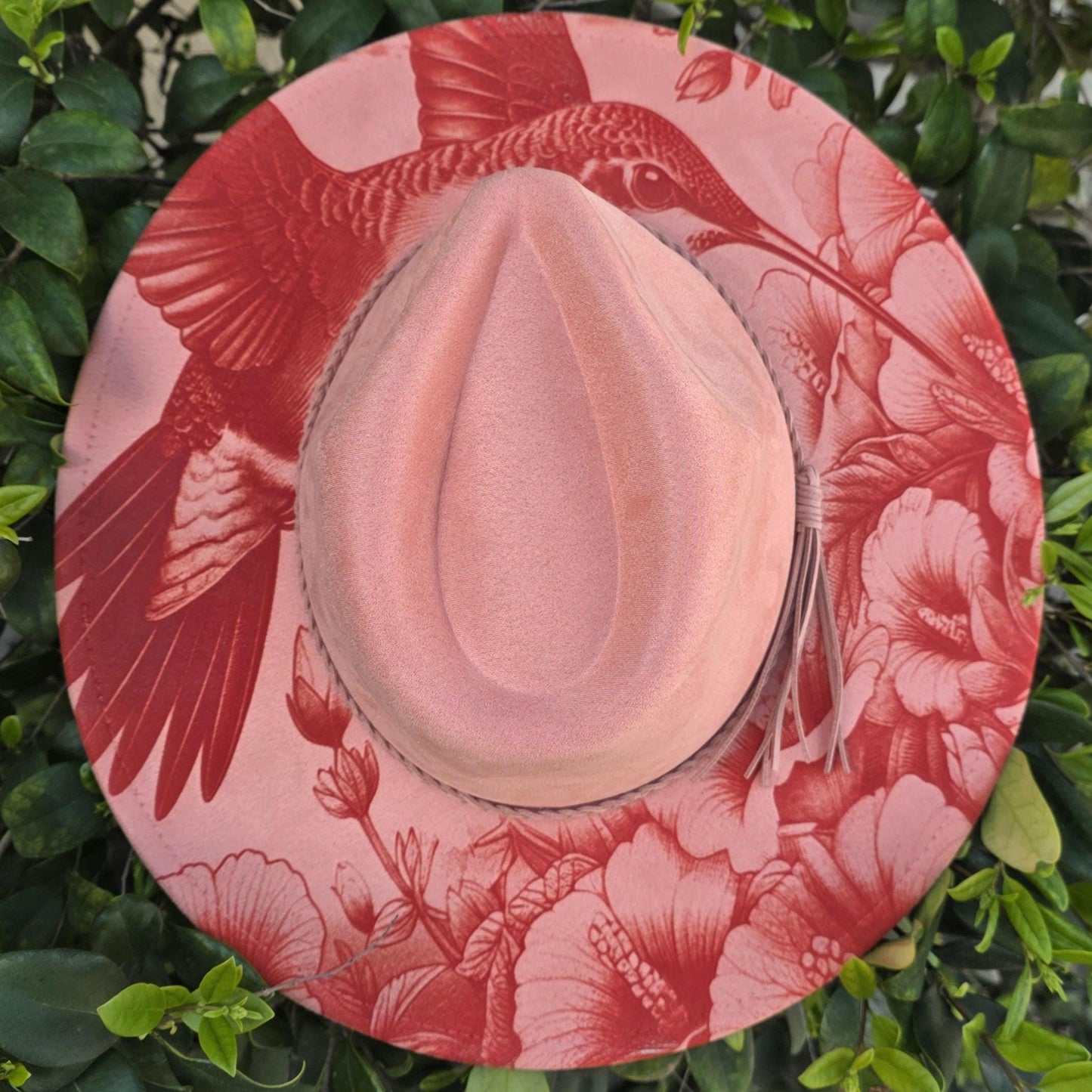 Laser engraved hummingbird and floral design on coral vegan suede wide brim hat styled outdoors in greenery