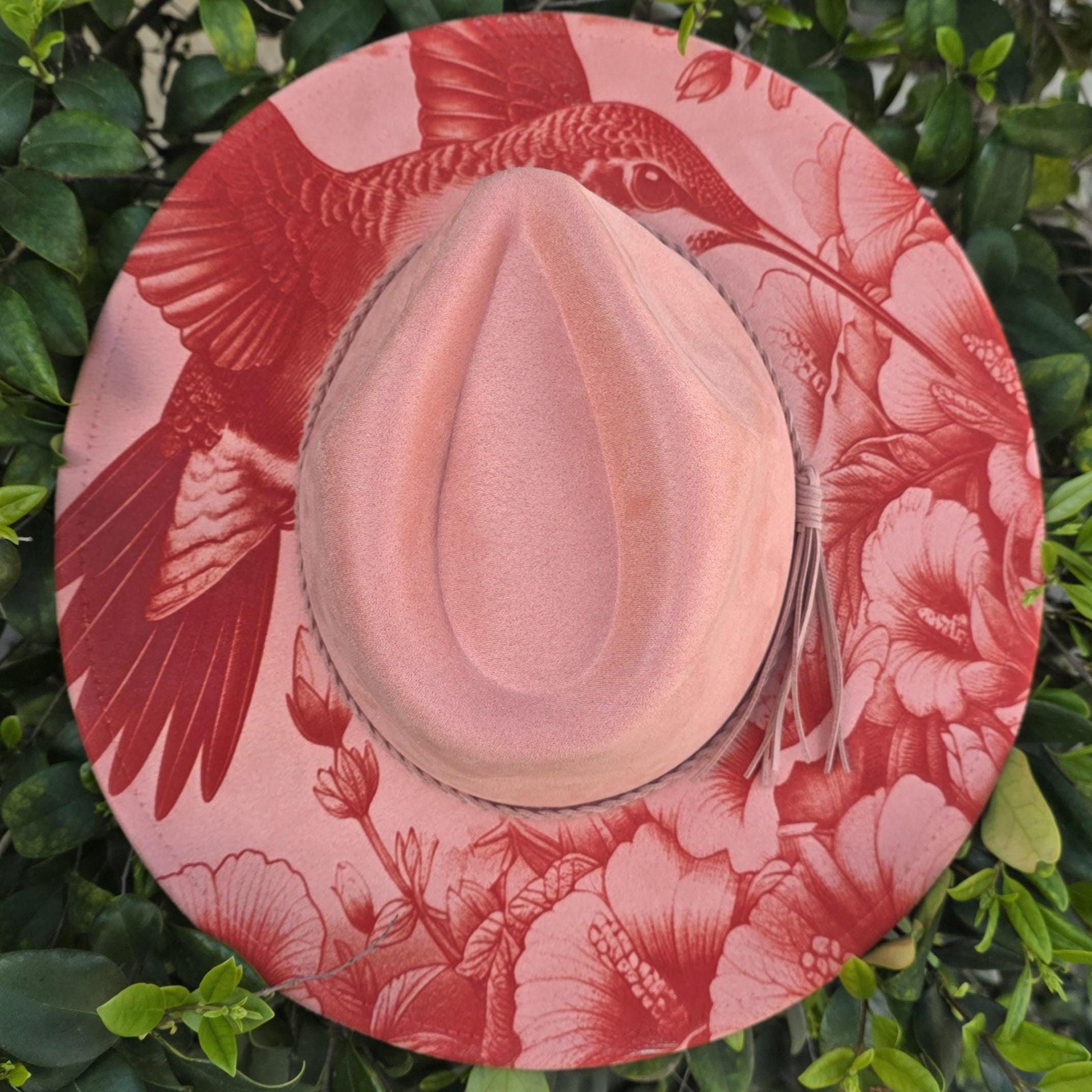 Laser engraved hummingbird and floral design on coral vegan suede wide brim hat styled outdoors in greenery