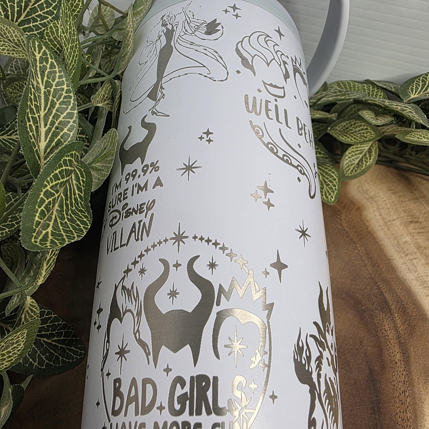 a white cylindrical object with various designs and text printed on it, surrounded by green leaves.